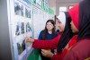 Neo from the Malaysia team chats with two female school pupils are they look at a wall display thumbnail